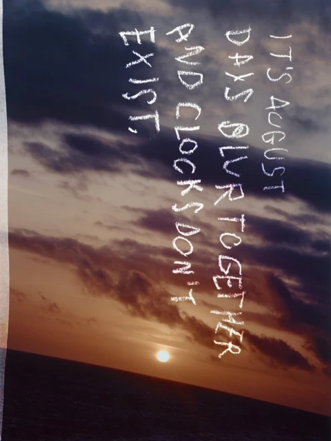 Sunset over the ocean with superimposed text that reads, 'It's August, days blur together, and clocks don't exist,' creating a serene visual.