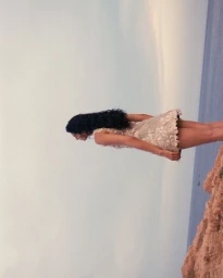 Model wearing a textured lace dress standing on a cliff edge overlooking the sea for Grazia UK Sunkissed Style editorial.