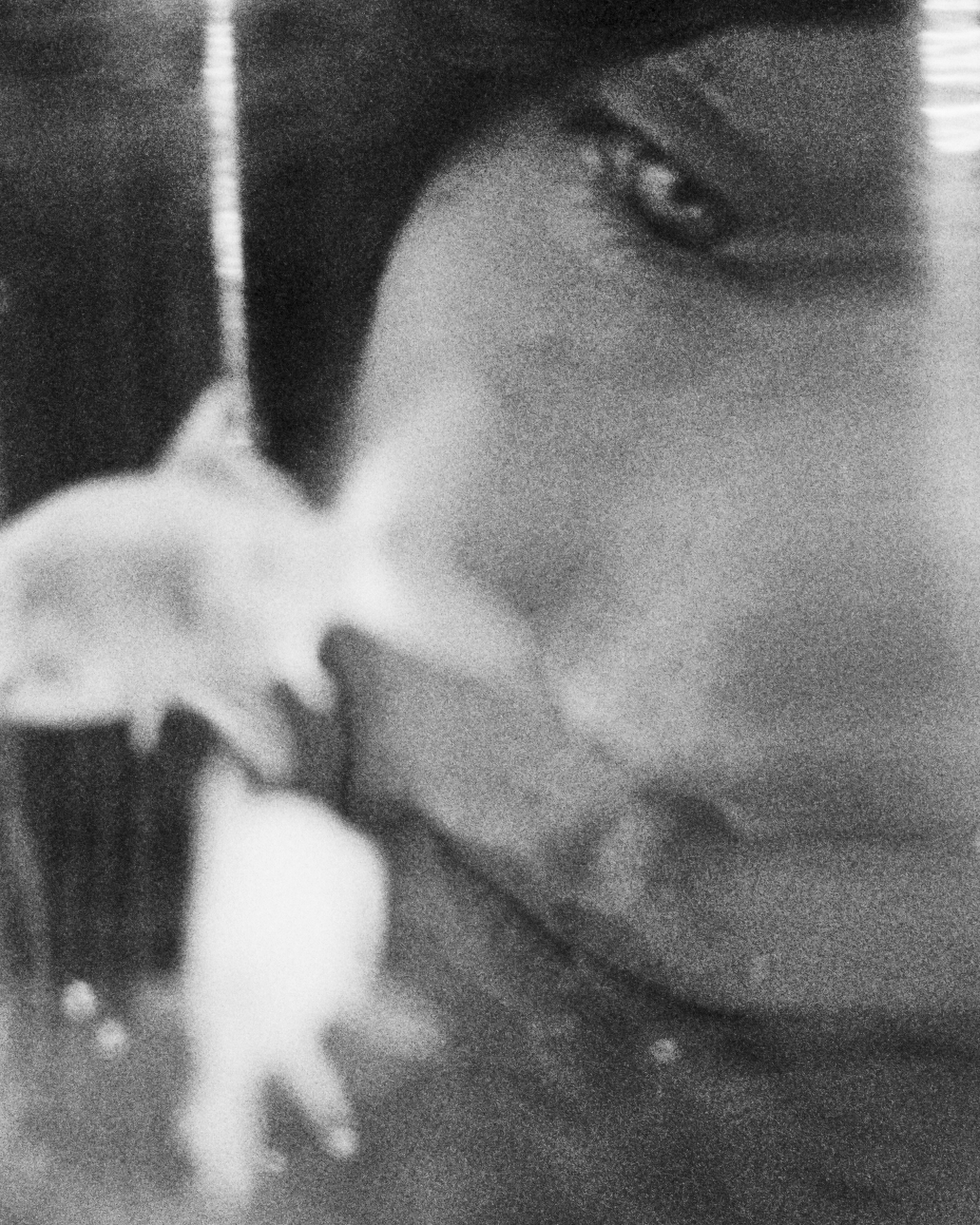 Close-up black and white portrait of a face with a blurry fish swimming nearby, creating an abstract and ethereal aesthetic.