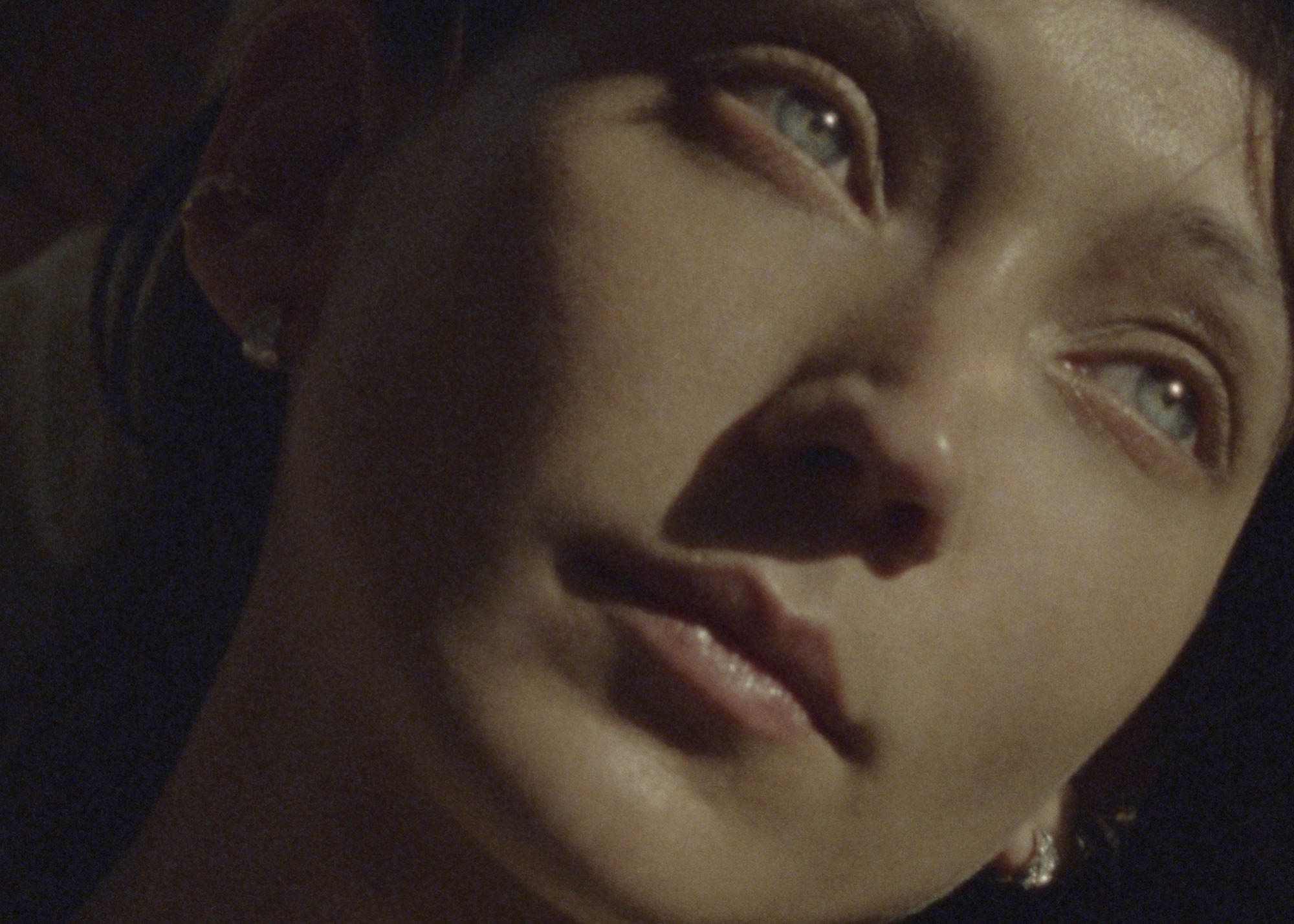 Close-up portrait of a woman with blue eyes and earrings in low-key lighting for Chanel