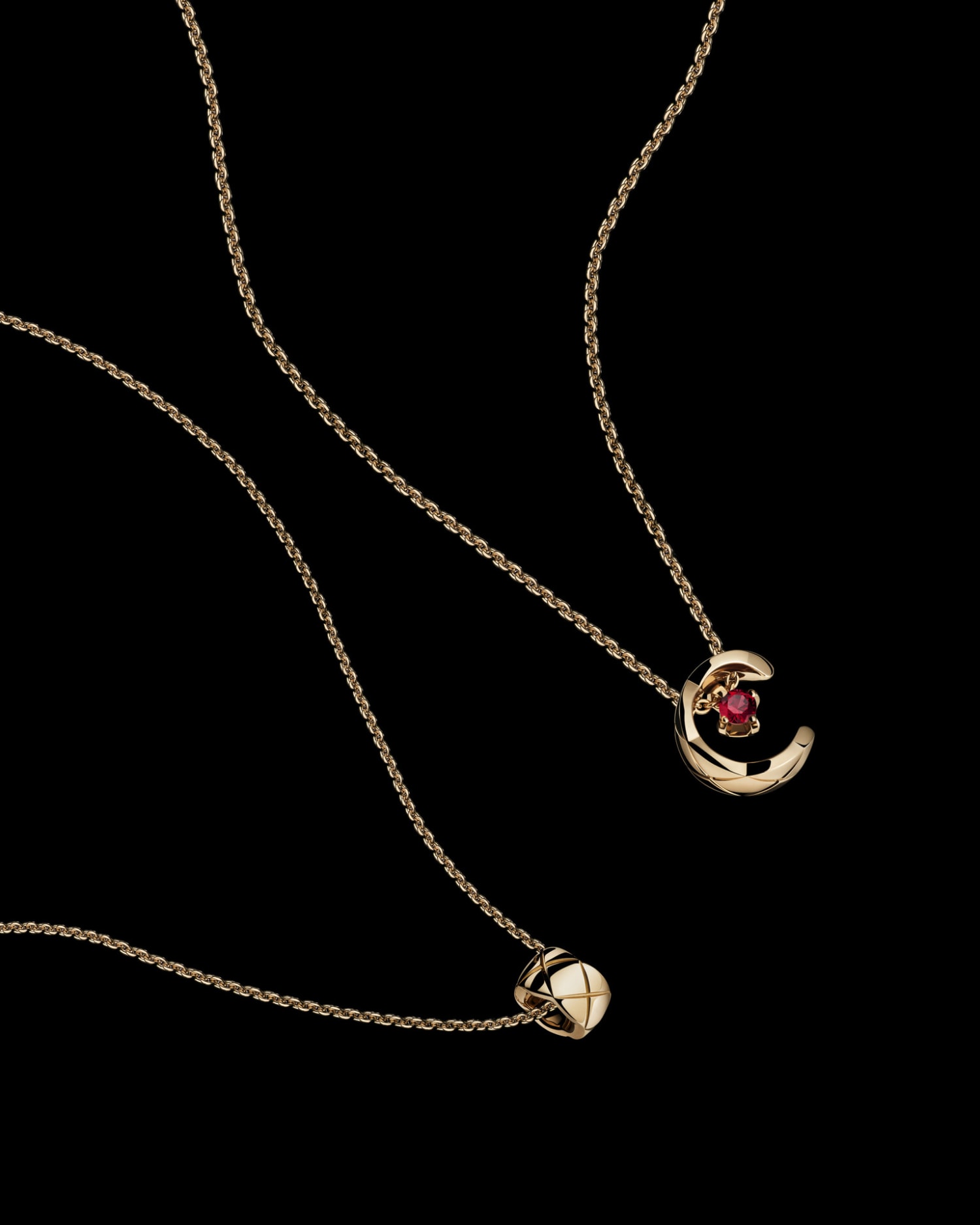 Elegant gold necklaces with ruby accents on a sleek black background. Fine jewelry photography for fashion and luxury brands. Close-up view.