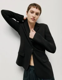 Model with short brown hair wearing a tailored black blazer against a neutral white background