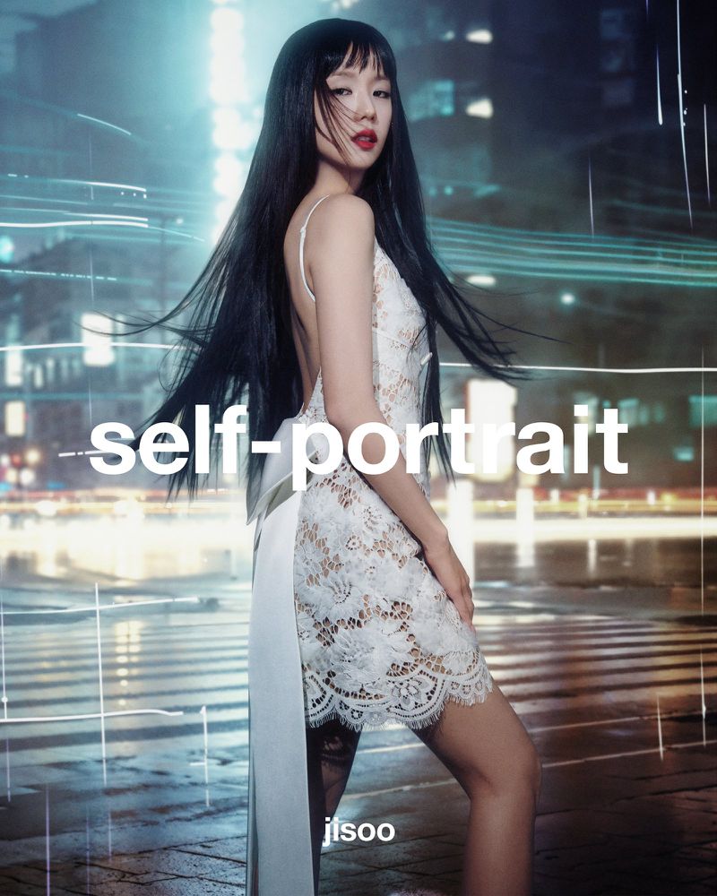 A woman in a white lace dress poses against an out-of-focus city background at night, featuring long black hair and a self-portrait theme.