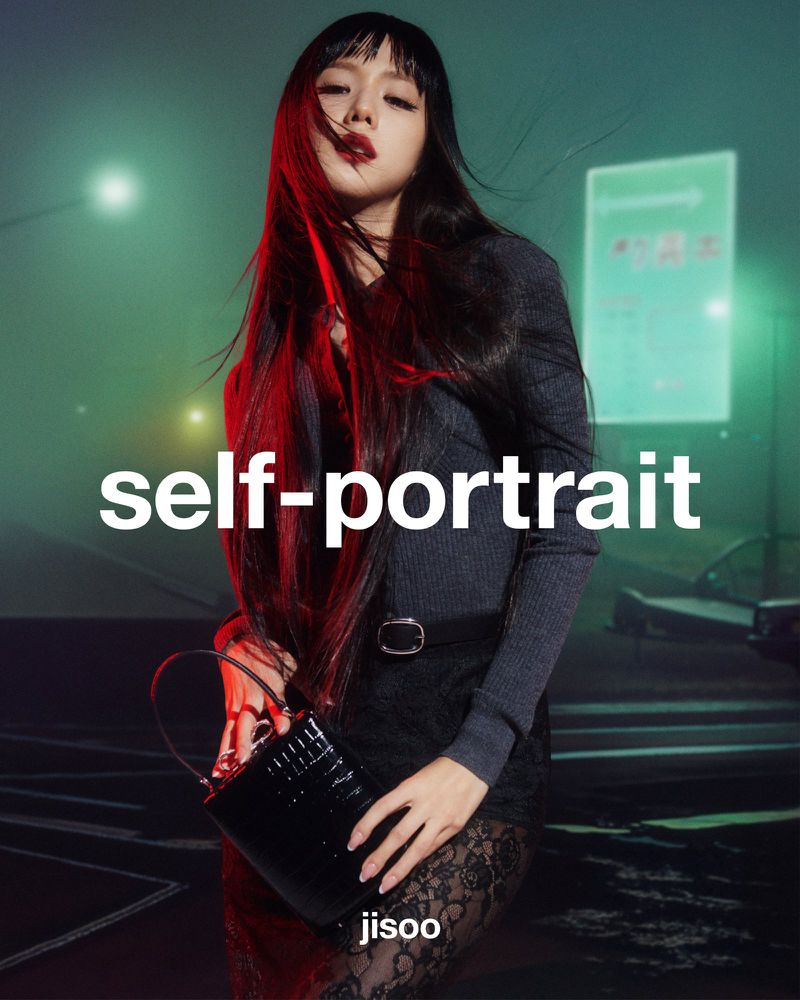 An Asian adult woman with long dark hair poses with a shiny black purse, wearing a grey top and black skirt, against an urban street background.