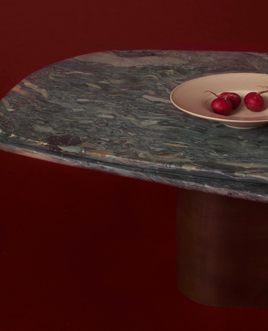 Radishes arranged on a plate placed on a marble table with a cylindrical base, all set against a dark red background.