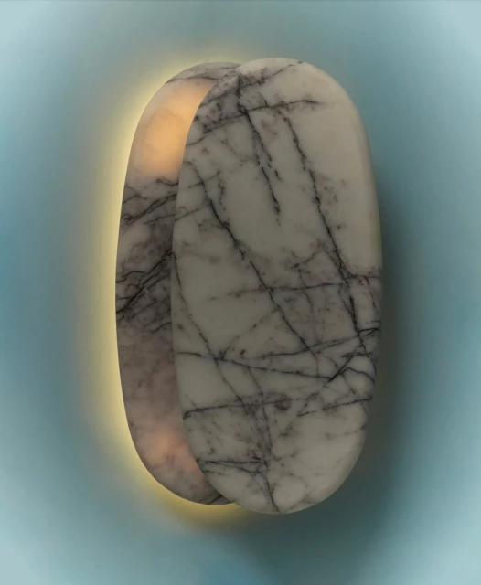 Close-up of a pair of marble wall sconces featuring a white marble finish with black veining and a soft, warm glow, mounted on a light blue wall.