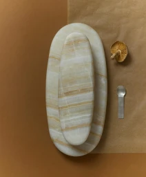 Two oval marble trays layered together on a neutral brown surface with a dried mushroom and small metal spoon.