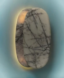 Sculptural oval marble wall sconce emitting a warm backglow against a pale blue wall for Just Adele's Oro Collection