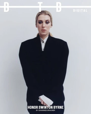 A magazine cover features Honor Swinton Byrne in a dark blazer and collared shirt against a bright white backdrop with bold sans-serif typography.