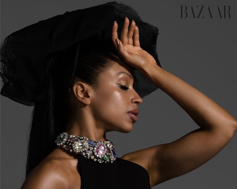Adult woman in profile, wearing couture headpiece and statement jewelry. Evening light in a fashion editorial for Bazaar magazine.