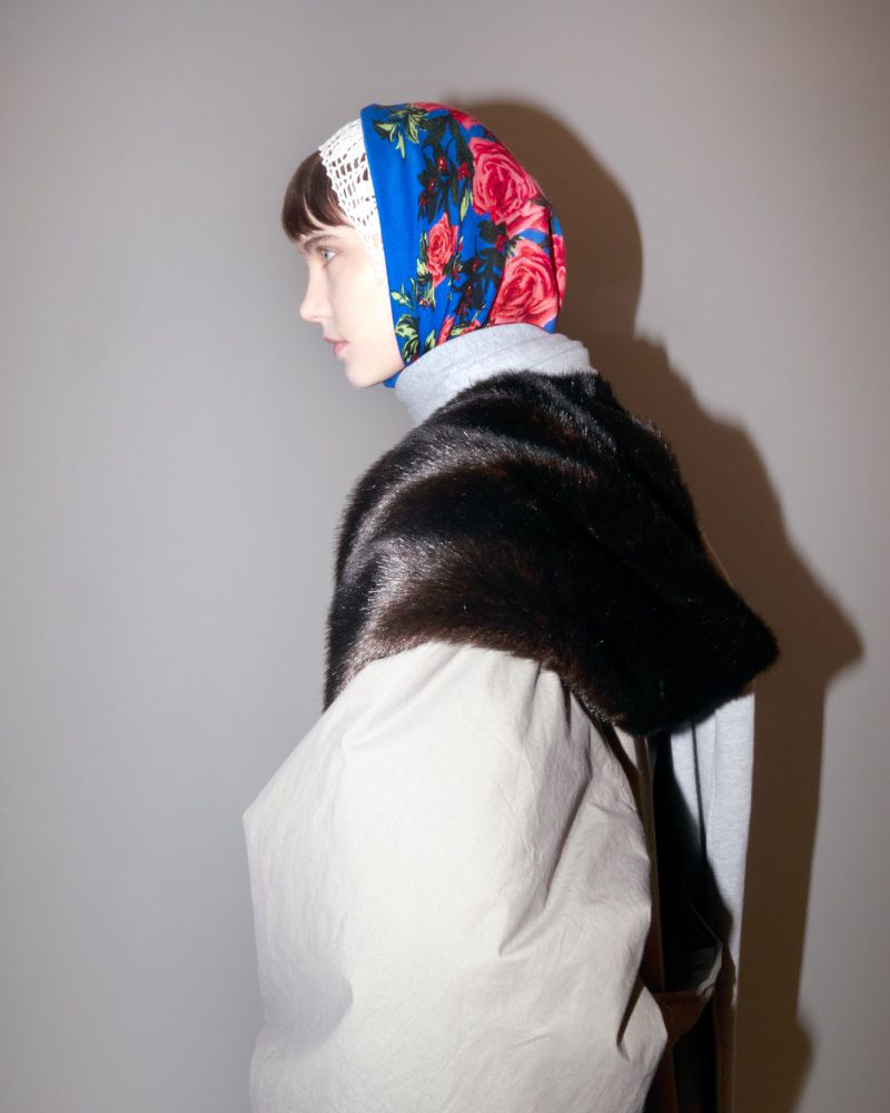 Adult female model wearing floral headscarf and fur stole poses indoors. Fashion, beauty, and style concept image.