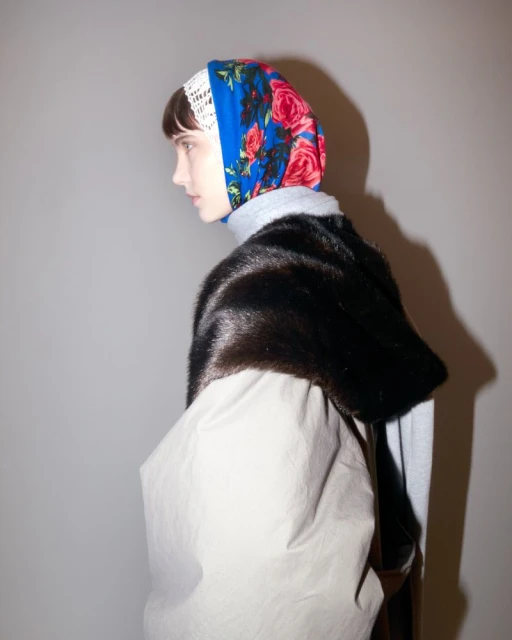 Adult female model wearing floral headscarf and fur stole poses indoors. Fashion, beauty, and style concept image.