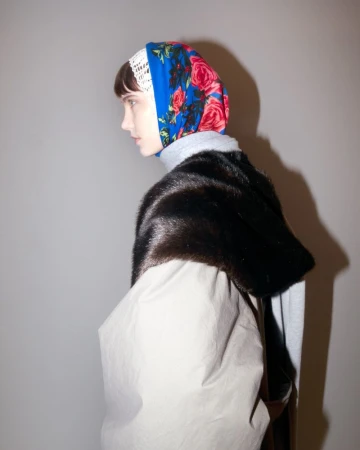 Adult female model wearing floral headscarf and fur stole poses indoors. Fashion, beauty, and style concept image.