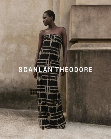 Model Achok Akoi in a strapless black embroidered column gown standing beside a textured stone wall for Scanlan Theodore.