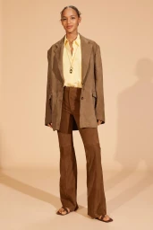 Model wearing a brown suede blazer, yellow shirt, and brown pants against a plain studio background.
