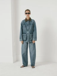 Model wearing a blue denim jacket with contrast collar and matching denim trousers against a white backdrop.