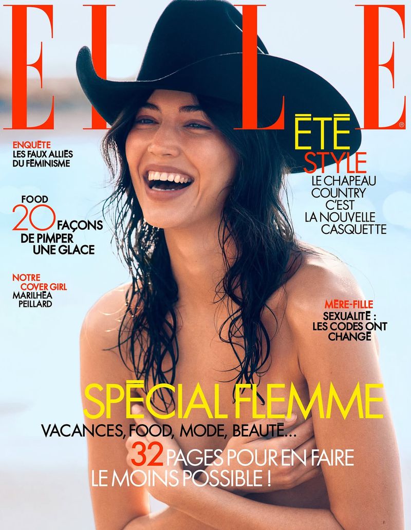 Elle magazine cover features a smiling woman in a cowboy hat, set against a blurred beach backdrop, promoting fashion, food, and vacation content.