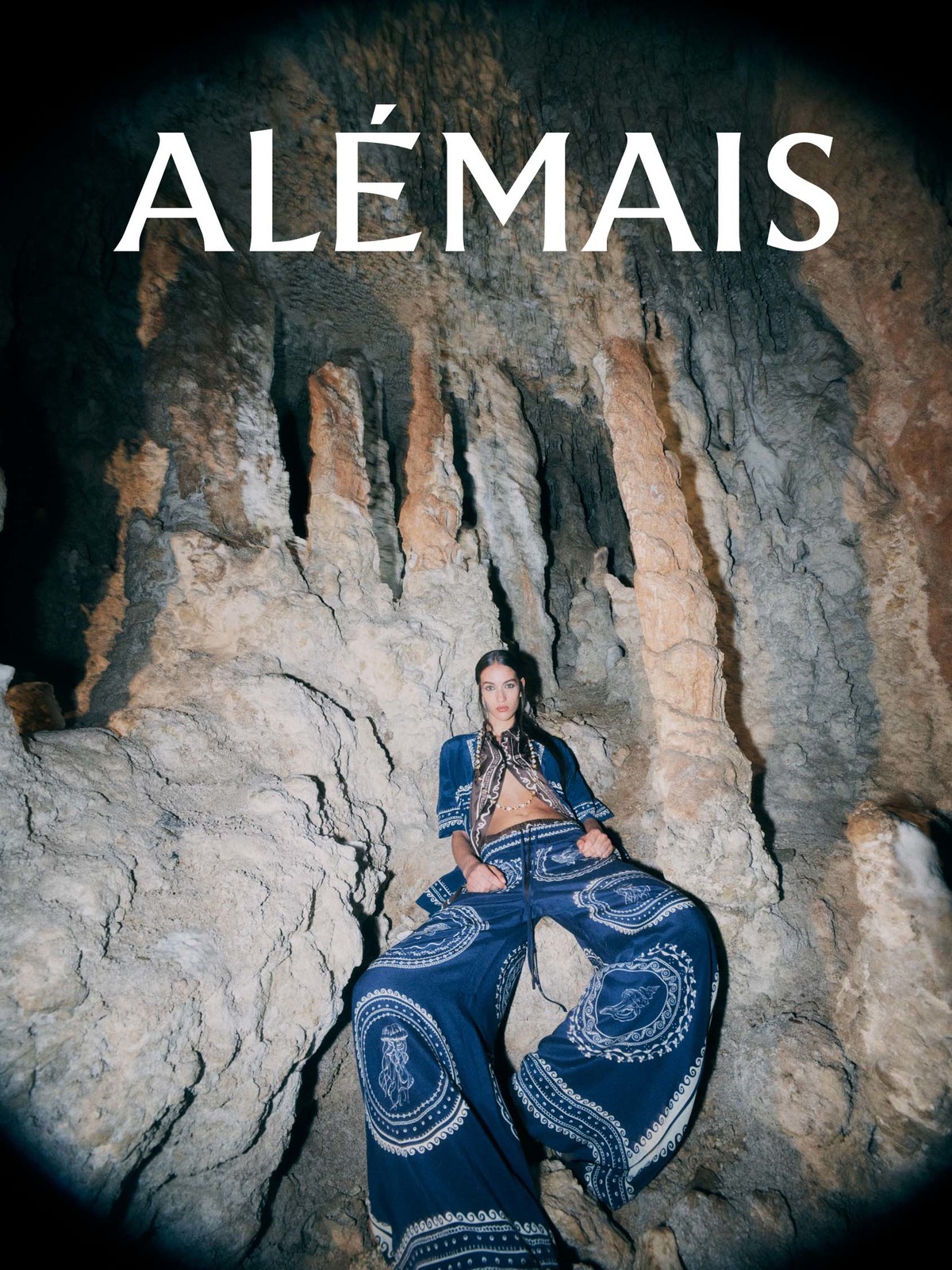 A fashion shot features a woman wearing a patterned blue outfit, inside a cave with dramatic lighting. The word "ALÉMAIS" is at the top.