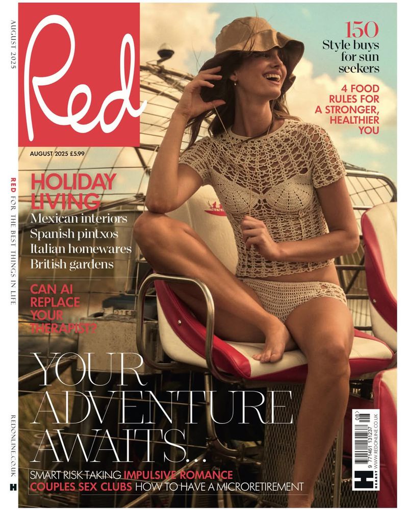 Magazine cover featuring a woman in crochet swimwear and a hat, smiling while sitting on a red and white seat outdoors on a sunny day.