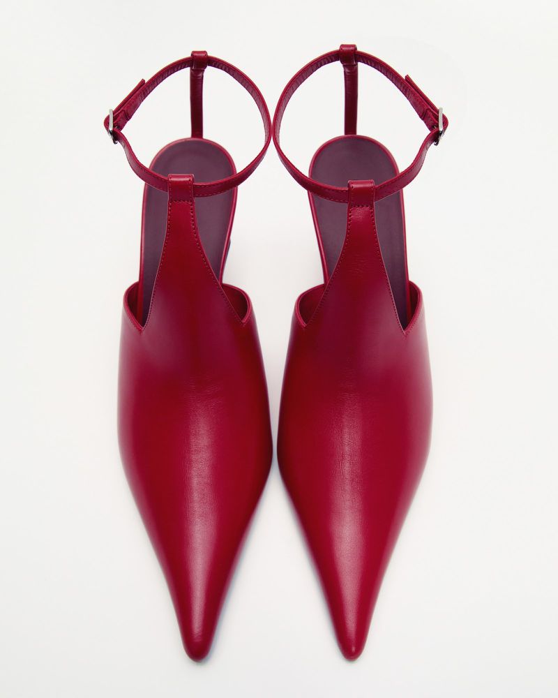 Pair of red heeled shoes with ankle straps. Pointed toe, shiny material, and light background for e-commerce or catalog display.