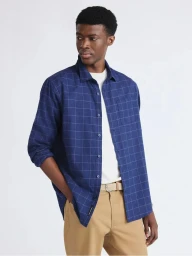 Model Jefferson Obuseri wearing a blue windowpane check shirt over a white tee with khaki chinos against a seamless background.