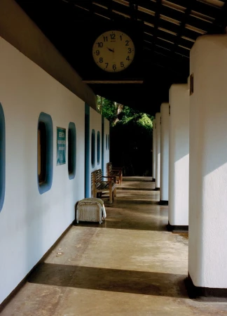 Hallway view with benches and natural light features an analog clock hanging on the wall, enhancing the visual appeal of the architecture.