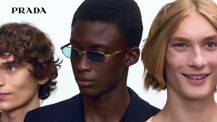 Close-up of three models wearing eyewear against a plain white background with Prada logo visible in top left