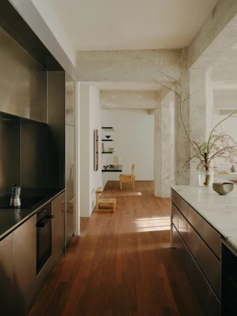 Modern kitchen and hallway in minimalist style. Features stainless steel kitchen units, wooden floor, and neutral-toned walls and ceiling.