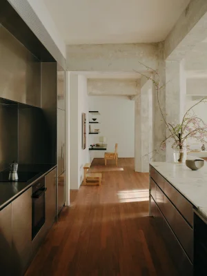 Modern minimalist kitchen interior with stainless steel cabinetry, marble island, and warm hardwood flooring.