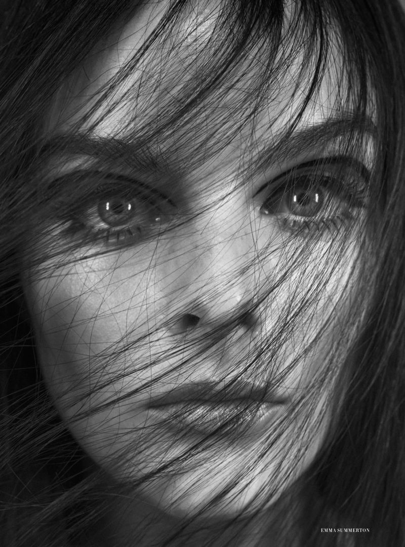Monochrome close-up portrait of model Aylah Peterson with fine dark hair strands blowing across her face and eyes gazing forward.