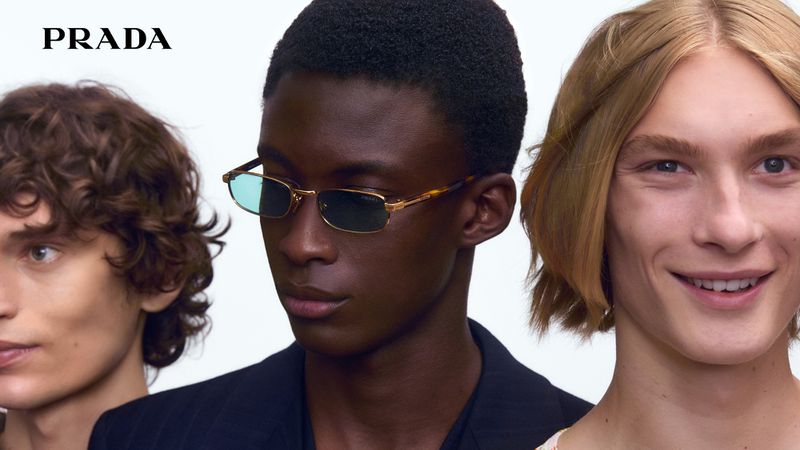 Fashion advertisement features a group of three young adult men modeling eyewear, showcasing diversity in skin tone and hair textures.