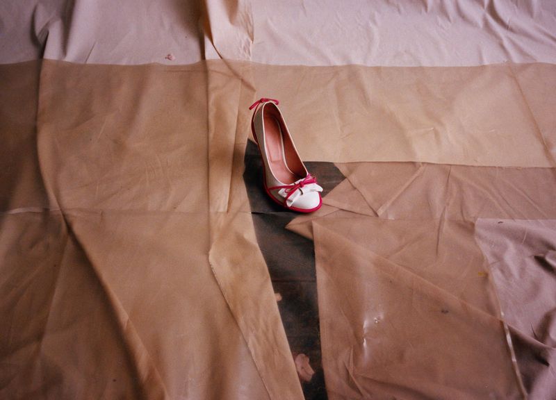 Elegant women's heel with white and pink accents displayed on crumpled tan fabric creating soft, diffused lighting and a fashion-forward aesthetic.