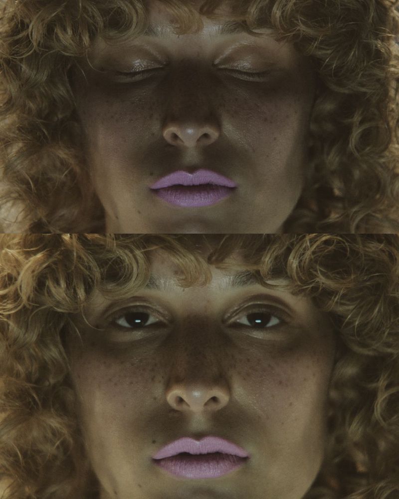 A split-screen close-up captures a young woman's face, once with eyes closed and once with eyes open, freckled skin and curly hair.