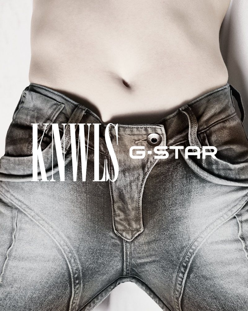 Close up of a person's torso wearing blue jeans in a studio. The waist and abdomen area are visible in a fashion forward context.