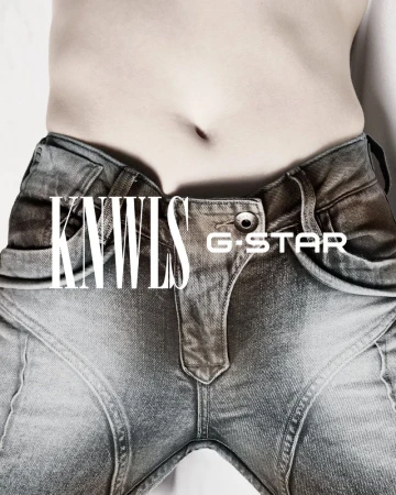 Close up of a person's torso wearing blue jeans in a studio. The waist and abdomen area are visible in a fashion forward context.