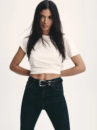Model wearing a white t-shirt and dark denim jeans with a black belt against a white background for Veronica Beard.