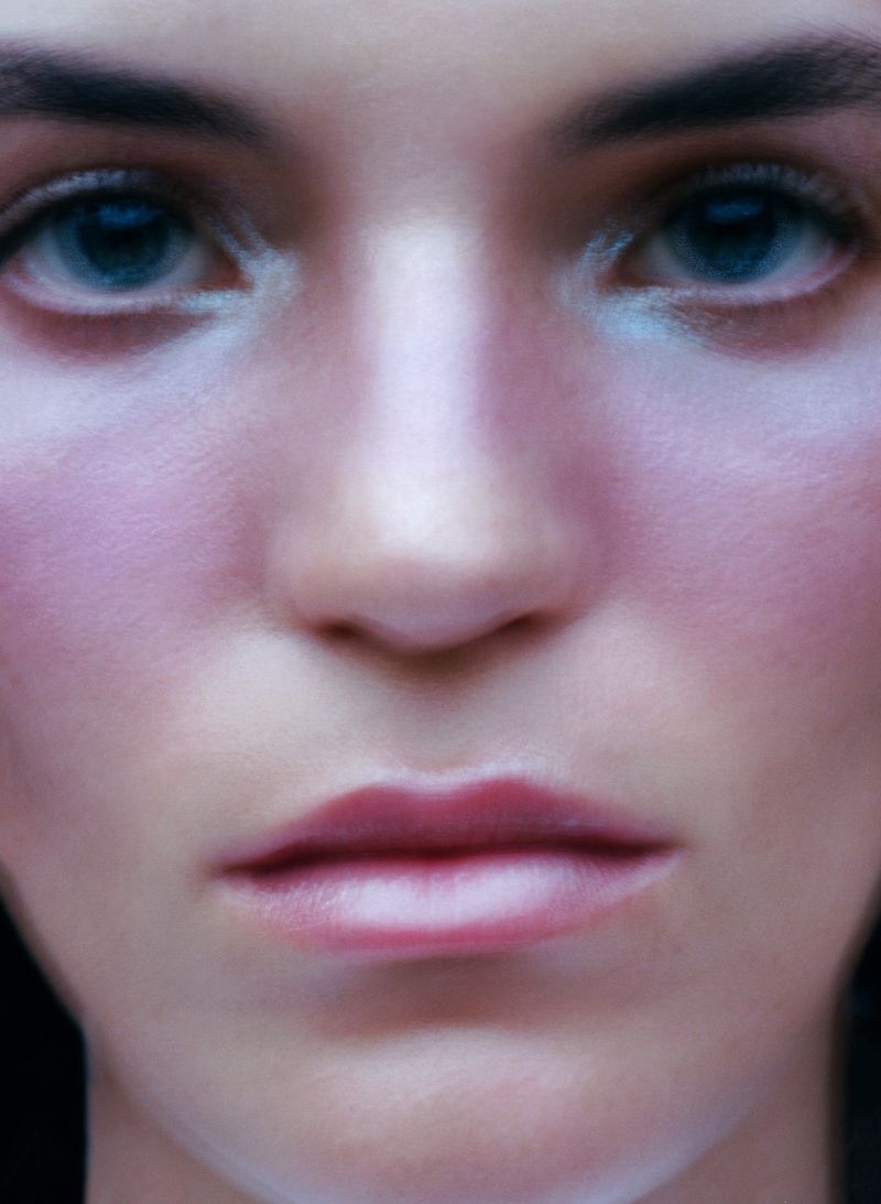 Close-up portrait of an adult female with light skin, blue eyes, and light pink makeup, focused on beauty and visual appeal.