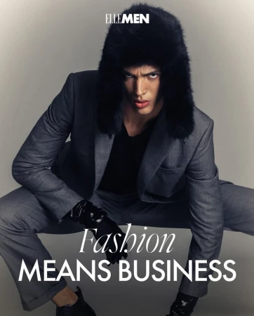 Man in a grey suit and fur hat poses for Elle Men fashion editorial, emphasizing sleek style against a neutral backdrop.