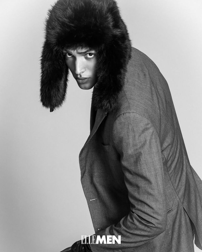 Portrait of a man in a grey suit and fur ushanka hat against a white background, fashion photography, black and white.