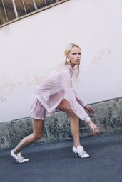 Model in pale pink pleated blouse and matching shorts posing against an outdoor wall for Spaghetti Magazine