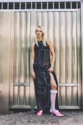 Model Roos Schreiner in a black dress standing against a metallic panel door for Spaghetti Magazine by Nicola Surbera