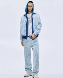 Model in light wash denim jacket and matching jeans with blue hoodie and white t-shirt against a plain white background