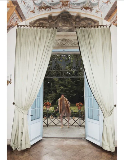 Model standing outdoors framed through open double doors with light green drapes for Madame Germany