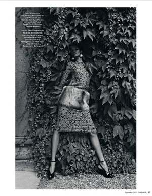 Black and white editorial fashion photograph of a model posing amidst dense ivy foliage wearing an animal print dress.