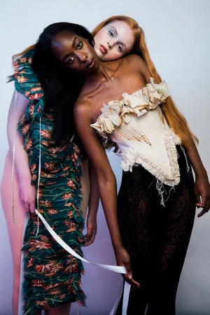 Ellie Goldstein and a model posing in textured corset and designer fashion against a studio backdrop for Schön Magazine.