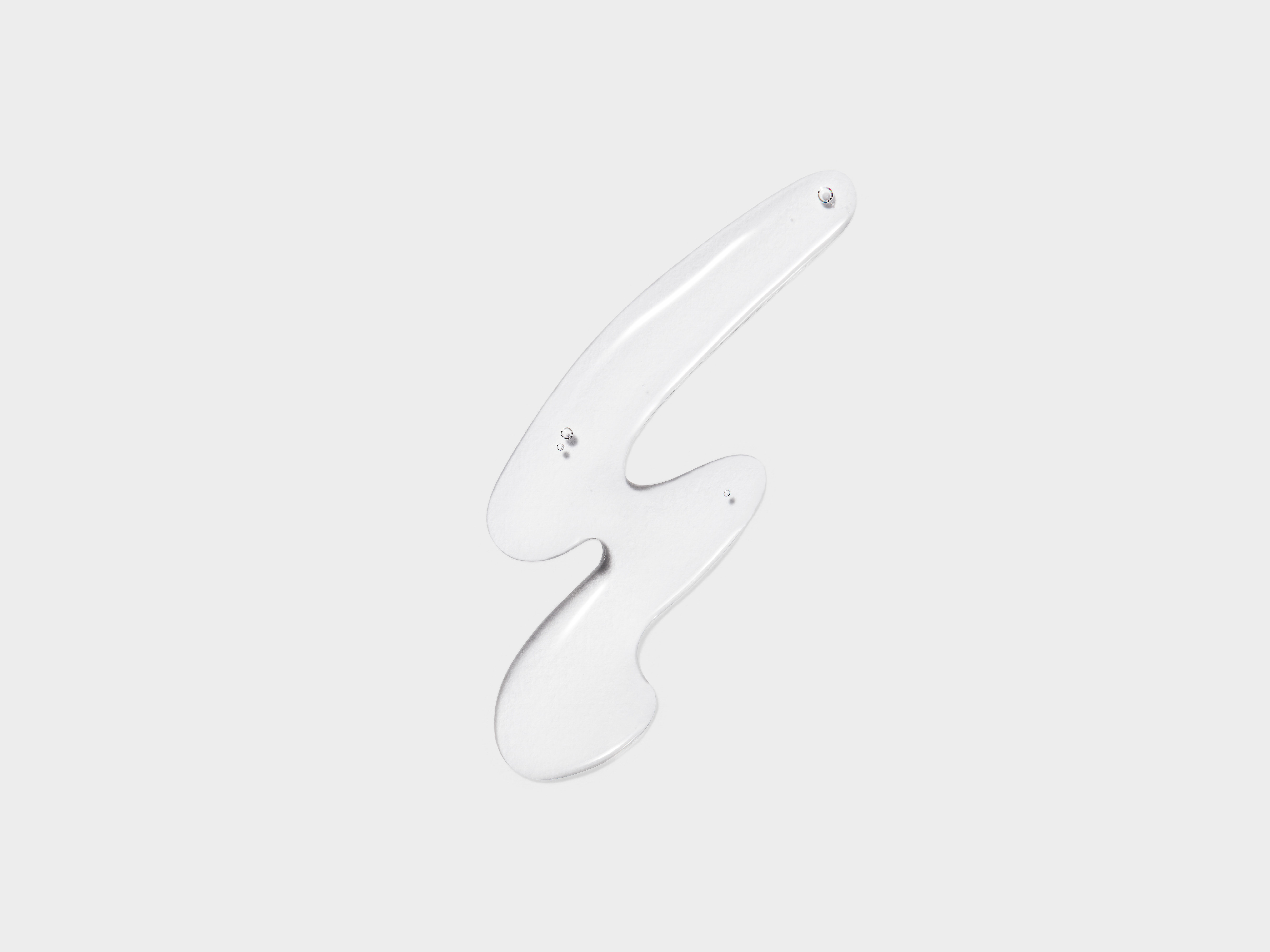 Clear liquid with abstract shape on a light gray background, product photography for skincare and beauty applications, studio lit scene.