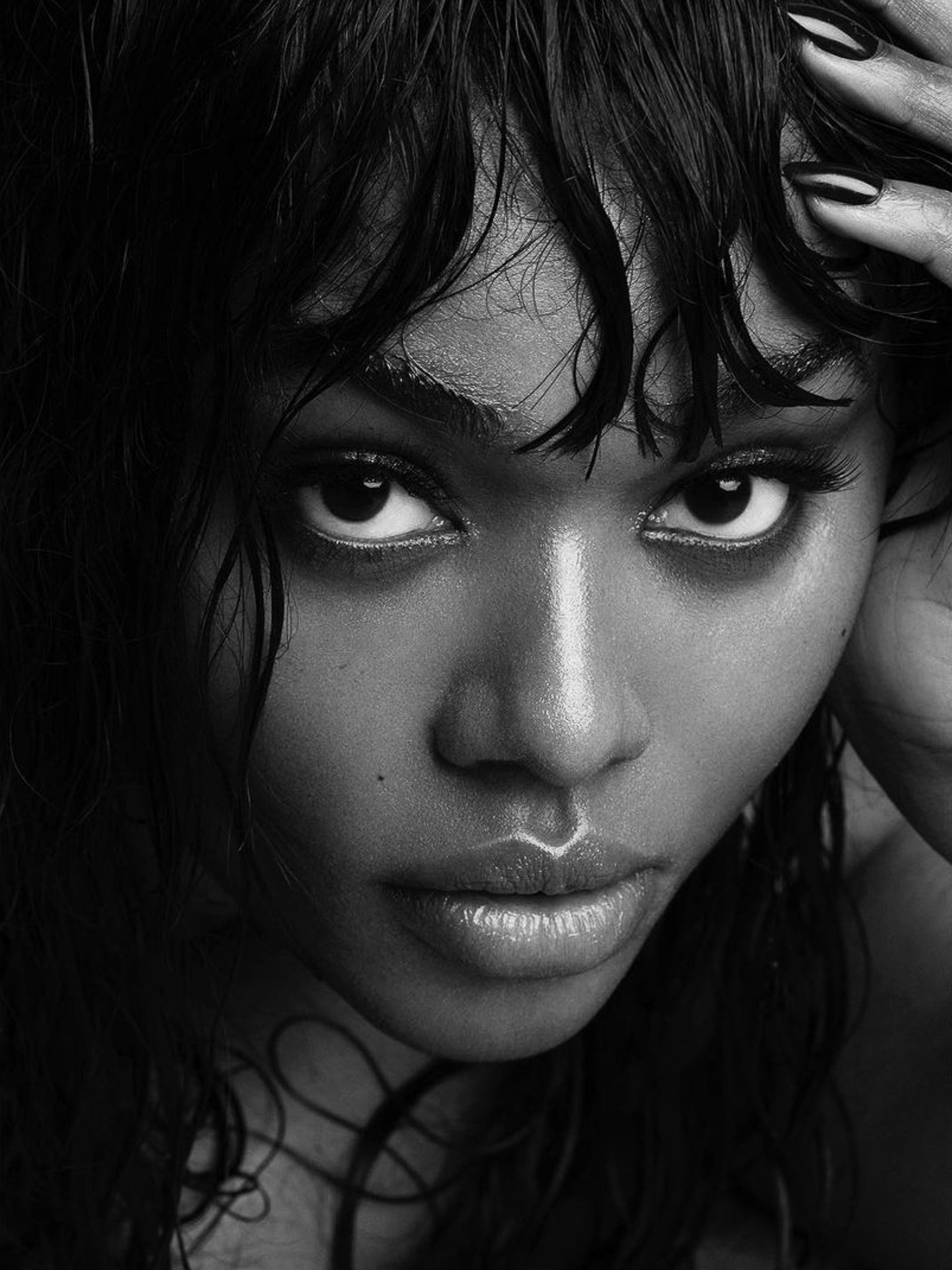 Striking black and white close-up portrait of a captivating adult female with wet hair, enhanced dark features, and polished dark nails.