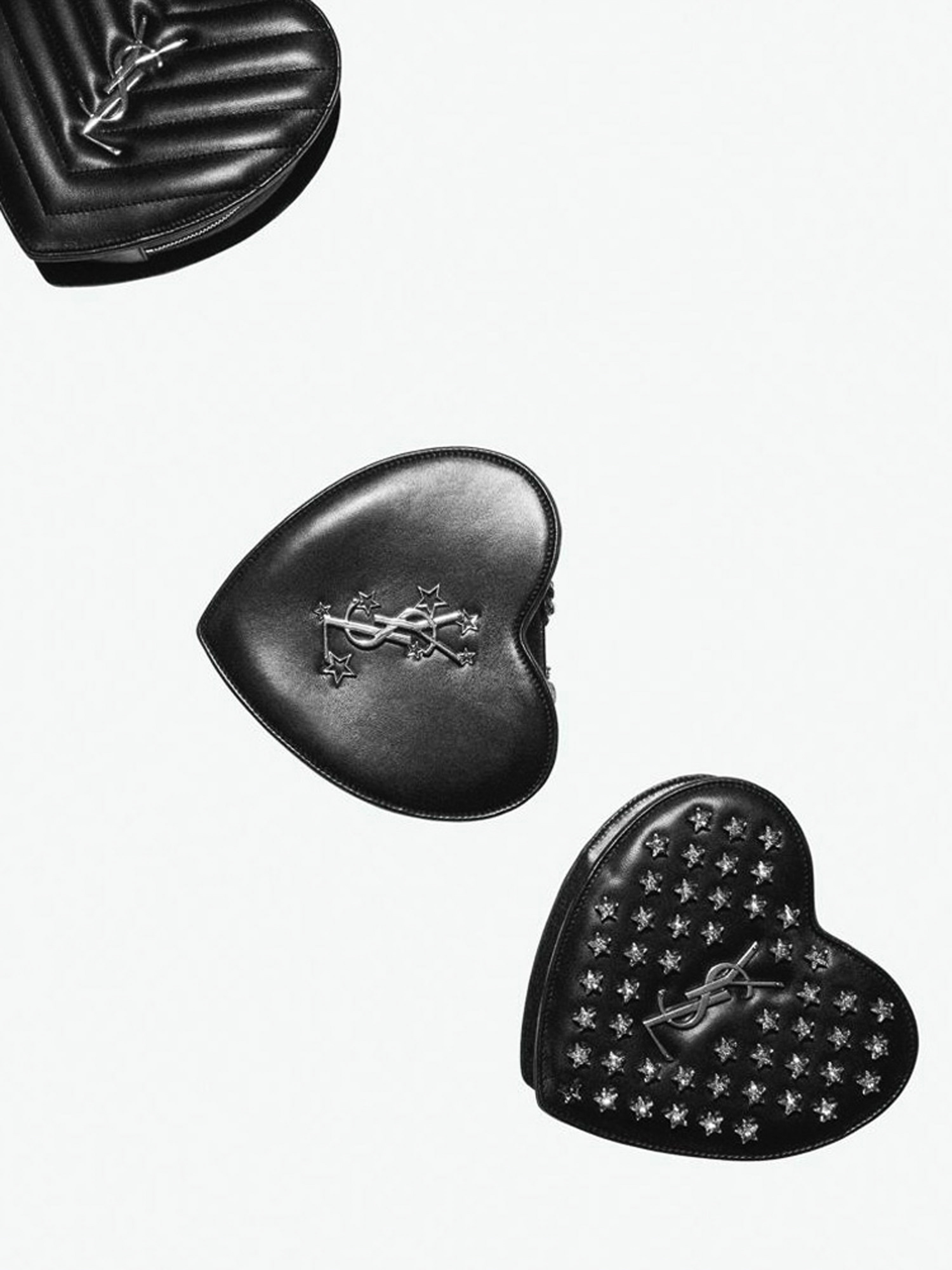 Three heart-shaped black leather handbags with silver logos and embellishments on a clean white background, high-fashion accessory.