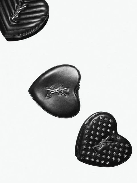 Three heart-shaped black leather handbags with silver logos and embellishments on a clean white background, high-fashion accessory.