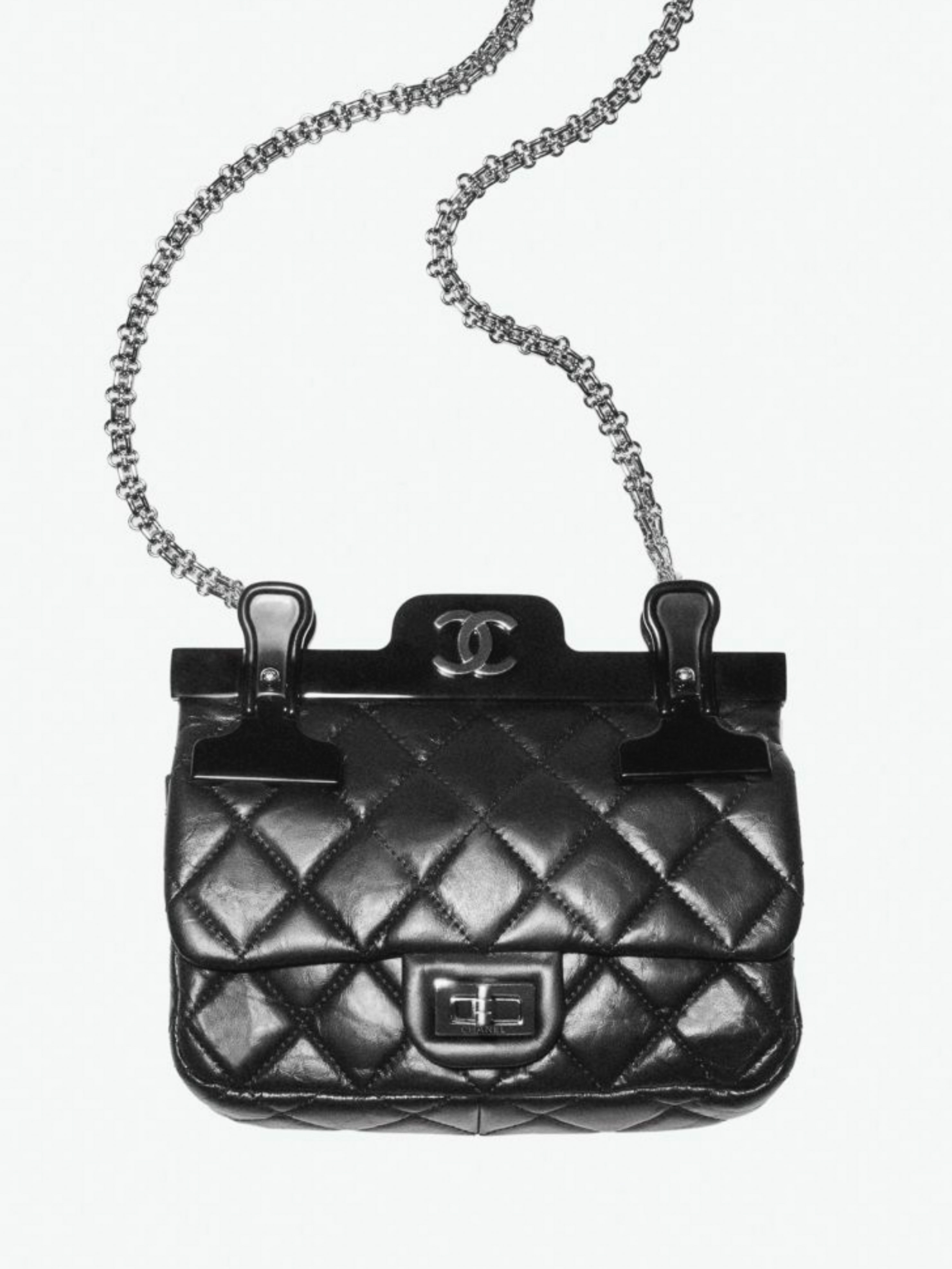 Black Chanel quilted handbag with metal chain strap and top clasp closure against a white background in a studio product shot.